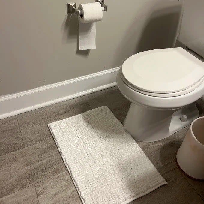 A reviewer photo of a small mat beneath a toilet