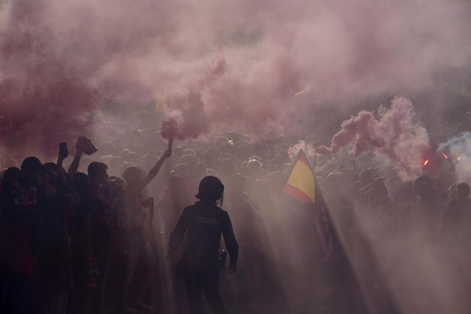 Police officers stand guard as supporters burn flares outside the Metropolitano stadium, ahead of the Champions League quarterfinal first leg soccer match between Atletico de Madrid and Dortmund in Madrid, Spain, Wednesday, April 10, 2024. This week's Champions League soccer games will go ahead as scheduled despite an Islamic State terror threat. (AP Photo/Andrea Comas, File)