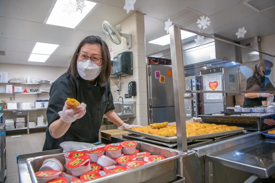 Rachel Wei, a substitute child nutrition team member, serves lunch to Timnath Elementary School students on Tuesday, Jan. 25, 2022, in Timnath, Colo.