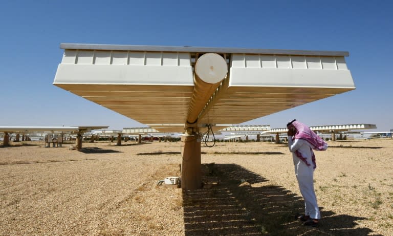 A man talks on his phone under a solar panel on March 29, 2018 in Uyayna, north of Riyadh, where Saudi Arabia is building what is set to be the world's biggest solar plant