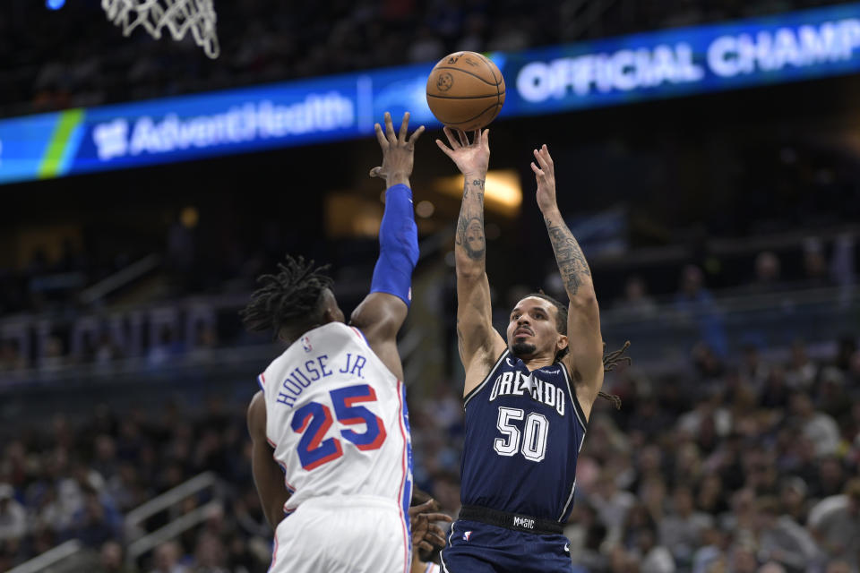 Orlando Magic guard Cole Anthony (50) shoots in front of Philadelphia 76ers forward Danuel House Jr. (25) during the first half of an NBA basketball game, Wednesday, Dec. 27, 2023, in Orlando, Fla. (AP Photo/Phelan M. Ebenhack)