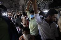 Indian commuters, some wearing protective masks as a precaution against COVID-19 travel in a crowded local train in Mumbai, India, Friday, March 20, 2020. For most people, the new coronavirus causes only mild or moderate symptoms. For some it can cause more severe illness. (AP Photo/Rajanish Kakade)