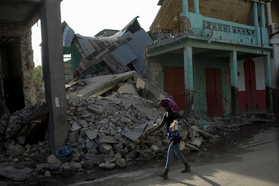 A woman walks past a collapsed building in Jeremie, Haiti, Wednesday, Aug. 18, 2021, four days after the city was struck by a 7.2-magnitude earthquake. (AP Photo/Matias Delacroix)