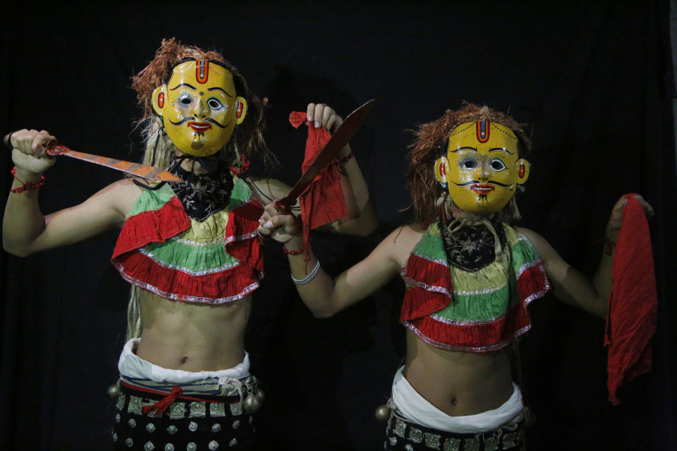 In this Sept. 23, 2018, photo, dancers pose for photographs wearing the mask of god Jangali in Kathmandu, Nepal. For centuries, Nepal has celebrated the Indra Jatra festival of masked dancers, which officially begins the month-long festivities in the Hindu-dominated Himalyan nation. The dancers, who come from a variety of backgrounds, pull off this performance every year despite minimal financial support from the government and other sources, they say. (AP Photo/Niranjan Shrestha)