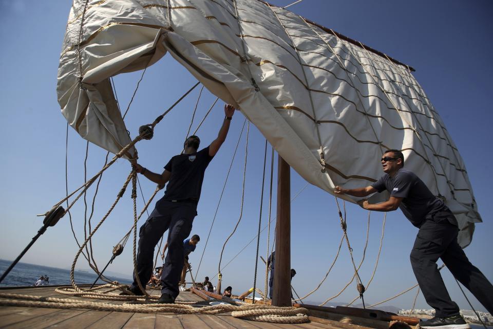 In this Sunday, Sept. 16, 2018 photo, Greek Navy sailors unfurl the sails of Olympias, replica of an ancient galley, at Saronic gulf in southern Athens. The 37-meter (121-foot) wooden vessel moored off southern Athens is an experimental reconstruction of the trireme, the sleek ancient Greek warship that halted a Persian invasion of Europe and ruled the Mediterranean for centuries. Every summer, visitors can get a whiff of life in the galleys 2,500 years ago by joining the crew of the Olympias _ and work up a sweat rowing it. (AP Photo/Thanassis Stavrakis)