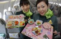 Flight attendants, holding Hello Kitty-themed in-flight meals, pose inside an Eva Airlines aircraft.