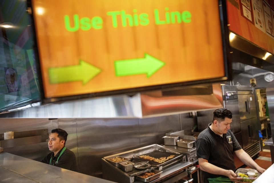 Carlos Gutierrez, left, and Marcos Morales prepare take-out orders at East Side Pockets, a small restaurant near Brown University, Wednesday, March 25, 2020, in Providence, R.I. While Trump is anxious to get the economy moving again, it's not clear businesses large or small are in a hurry to start up operations before the new coronavirus is under control. (AP Photo/David Goldman)