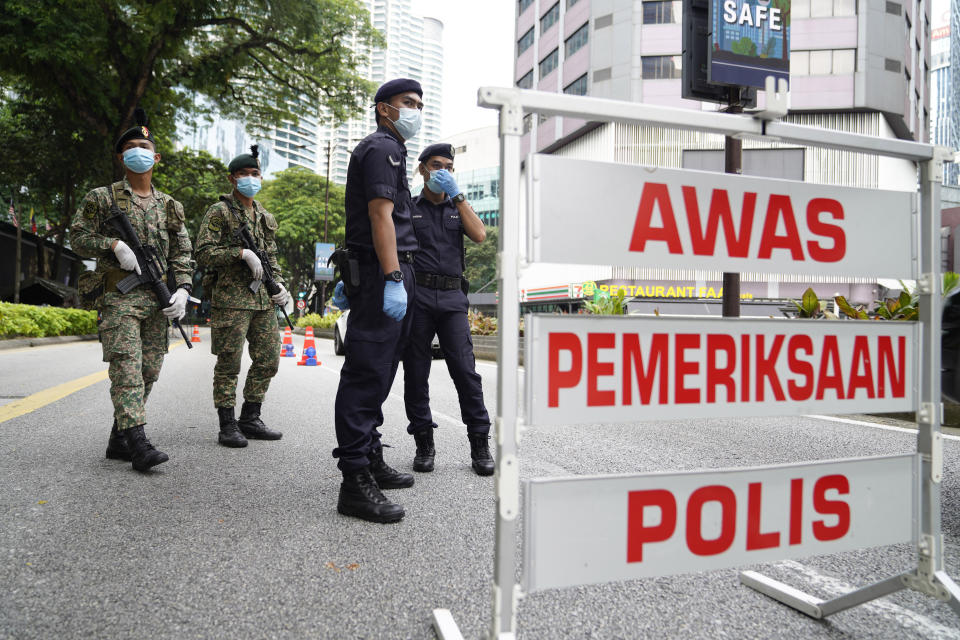 Police and army officers check vehicles at a roadblock to ensure that people abide by a movement control order in downtown Kuala Lumpur, Malaysia, Wednesday, Oct. 14, 2020. Malaysia will restrict movements in its biggest city Kuala Lumpur, neighboring Selangor state and the administrative capital of Putrajaya from Wednesday to curb a sharp rise in coronavirus cases. (AP Photo/Vincent Thian)