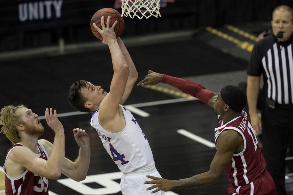 Kansas forward Mitch Lightfoot (44) shoots while covered by Oklahoma forward Brady Manek (35) and guard De'Vion Harmon (11) during the first half of an NCAA college basketball game in the quarterfinal round of the Big 12 men's tournament in Kansas City, Mo., Thursday, March 11, 2021. (AP Photo/Orlin Wagner)