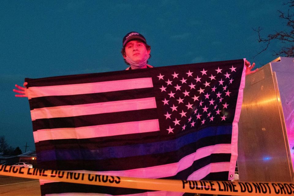 Zachary Smith holds a thin blue line flag in honor of Boulder Police officer Eric Talley who perished in the line of duty during an mass shooting at the King Soopers grocery store in Boulder, Colorado on March 22, 2021 (AFP via Getty Images)