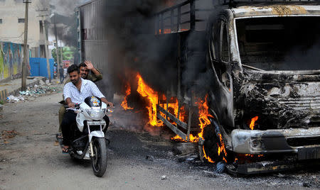 Men ride a motorcycle past a lorry in Bengaluru, India September 12, 2016. REUTERS/Abhishek N. Chinnappa/File Photo