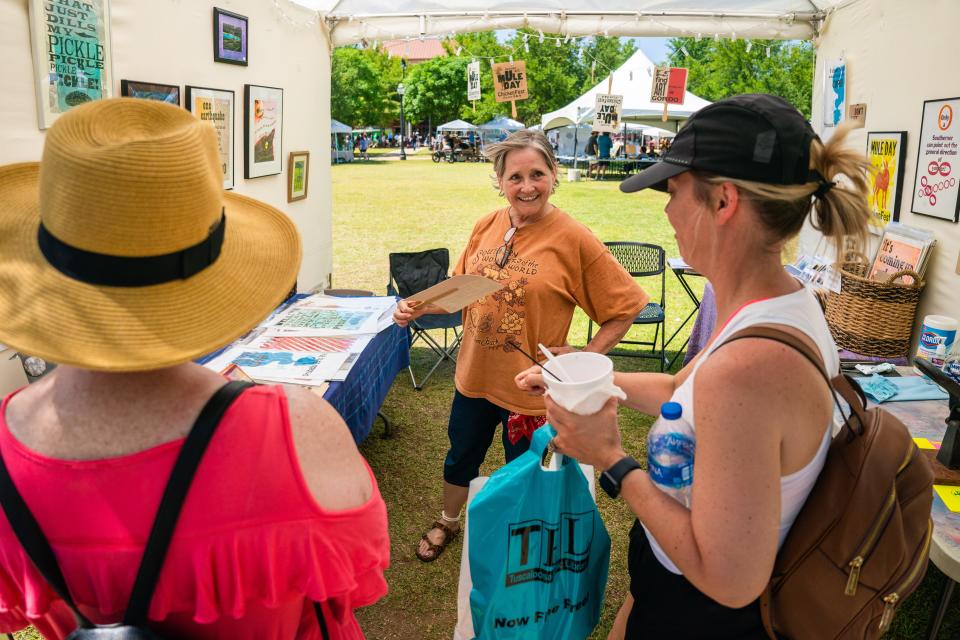 Sherri Warner of the Crossroads Arts Alliance talks to patrons interested in her work at the 2022 Druid City Arts Festival in Government Plaza.