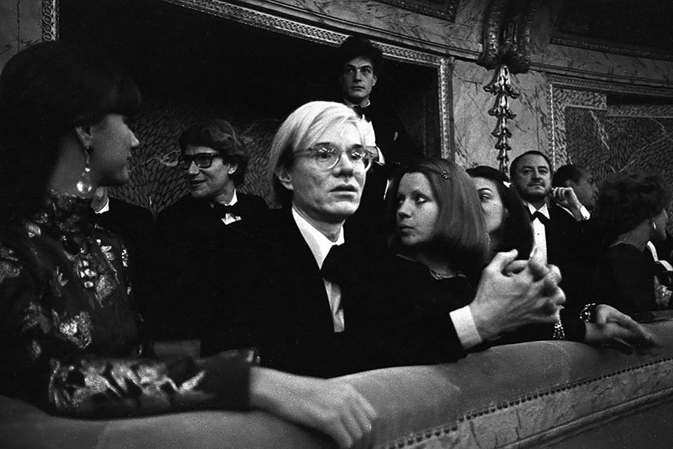 Exit;  Artist Andy Warhol sits with designers Yves Saint Laurent, Mary Russell and Pierre Berge during the fashion show organized to benefit the restoration of the Chateau de Versailles;  five American designers pair talents with five French couturiers at the Palace of Versailles in Versailles on November 28, 1973.  France...Article title: 