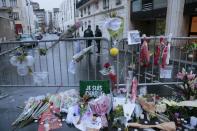 French police stand guard near floral tributes outside the Charlie Hebdo offices in Paris, on January 9, 2015