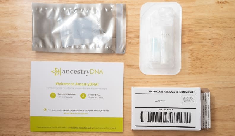 The contents of an AncestryDNA test kit, which features a spit tube, return package, and activation information.