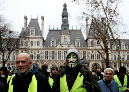 A protester in a yellow vest wearing a Guy Fawkes mask walks near Hotel de Ville during a demonstration by the "yellow vests" movement in Paris, France, January 5, 2019. REUTERS/Gonzalo Fuentes