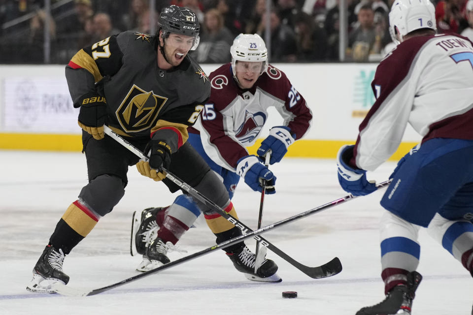 Vegas Golden Knights defenseman Shea Theodore (27) skates by Colorado Avalanche right wing Logan O'Connor (25) during the second period of an NHL hockey game Saturday, Feb. 26, 2022, in Las Vegas. (AP Photo/John Locher)