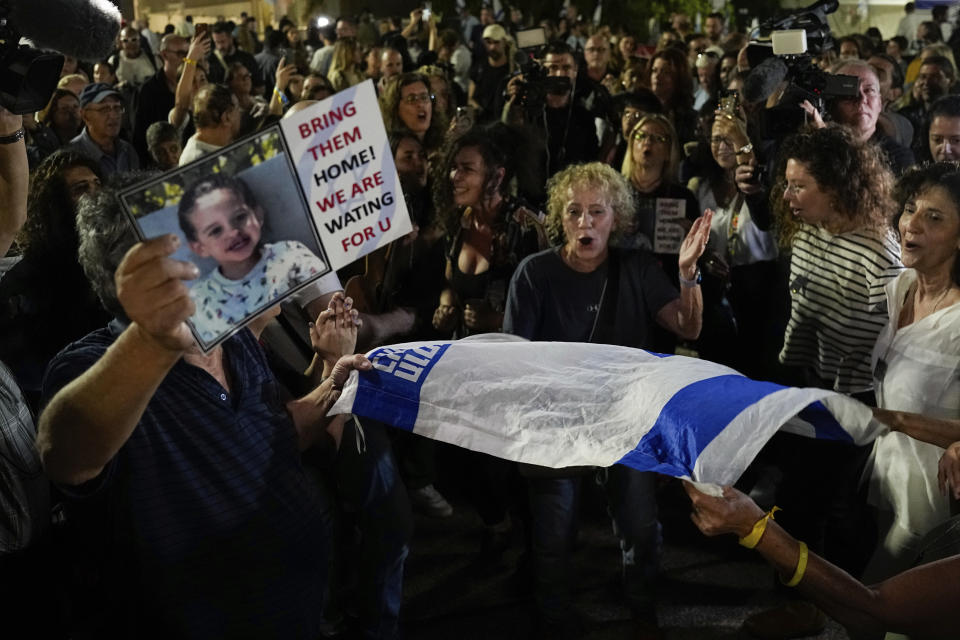 People react as they hear the news of the release of 13 Israeli hostages held by Hamas in the Gaza strip, in Tel Aviv, Israel, on Friday, Nov. 24, 2023. Friday marks the start of a four-day cease-fire in the Israel-Hamas war, during which the Gaza militants pledged to release 50 hostages in exchange for 150 Palestinians imprisoned by Israel. (AP Photo/Ariel Schalit)