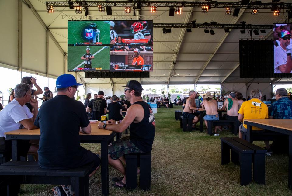 Festivalgoers take shade and watch Sunday sports action at the Holy Dive Bar at the Power Trip Music Festival at the Empire Polo Club in Indio, Calif., Sunday, Oct. 8, 2023.