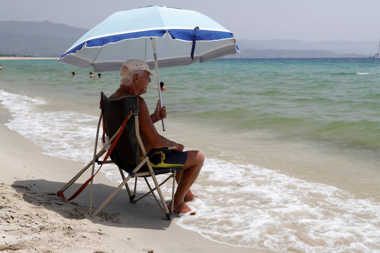 Un hombre se sienta bajo la sombra de una sombrilla en la playa Ricanto en Ajaccio, en la isla francesa de Córcega, el 19 de julio de 2023, mientras Europa es golpeada por una importante ola de calor. 