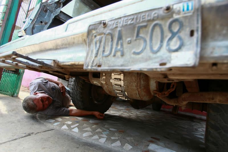 Alfredo Gonzalez checks a cooking gas canister beneath his car, which is used to run his vehicle instead of fuel, as Venezuelans struggling to cope with chronic fuel shortage, in Maracaibo