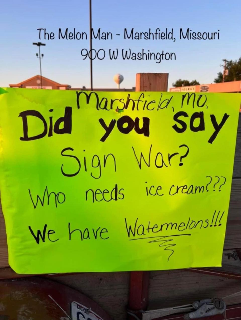 A handwritten sign says "Did you say sign war? Who needs ice cream? We have watermelons"