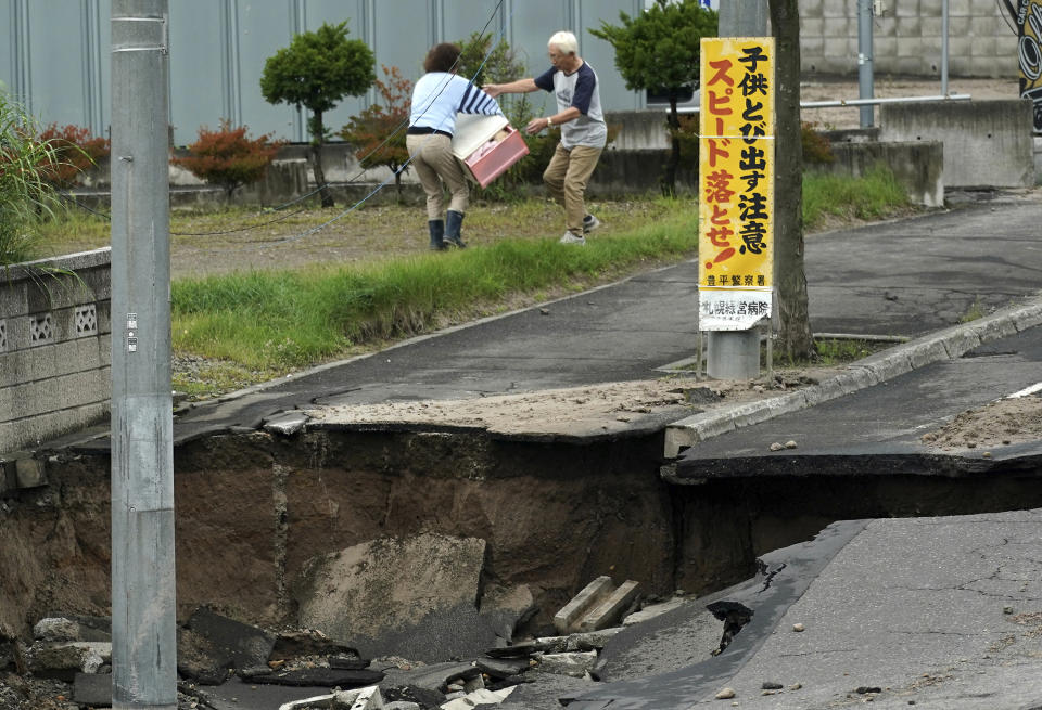 Residents bring out their belongings from an earthquake-damaged house in Kiyota ward of Sapporo, Hokkaido, northern Japan, Saturday, Sept. 8, 2018. Thursday's powerful earthquake hit wide areas on Japan's northernmost main island of Hokkaido. Some parts of the city were severely damaged, with houses atilt and roads crumbled or sunken. A mudslide left several cars half buried, and the ground subsided in some areas, leaving drainpipes and manhole covers protruding by more than a meter (yard) in some places. (AP Photo/Eugene Hoshiko)