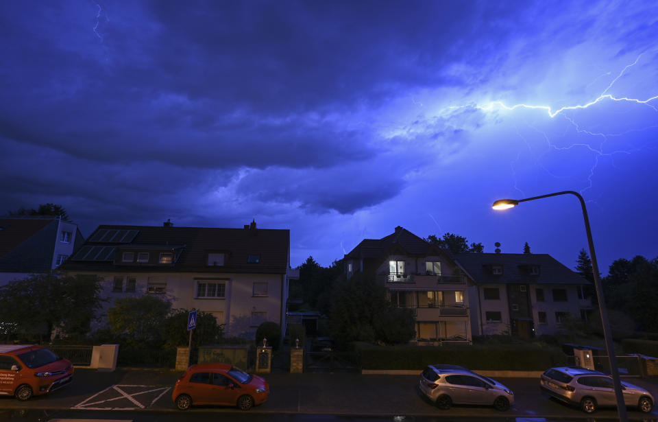 In this shot with slow shutter speed, lightning discharges in the evening sky during a heavy thunderstorm over the houses in the district of Sachsenhausen, Frankfurt/Main, Germany Wednesday, Aug. 16, 2023. Heavy rain in parts of Germany caused flooding and led to dozens of flight cancelations at Frankfurt Airport, the country's busiest and a major European hub, authorities said Thursday. (Arne Dedert/dpa via AP)
