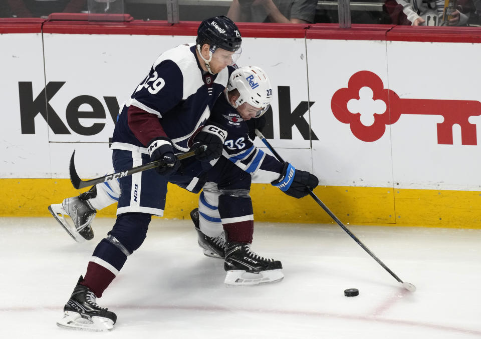 Colorado Avalanche center Nathan MacKinnon (29) fights for control of the puck against Winnipeg Jets center Karson Kuhlman during the first period of an NHL hockey game Thursday, April 13, 2023, in Denver. (AP Photo/David Zalubowski