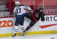 Winnipeg Jets center Adam Lowry, left, checks Ottawa Senators center Michael Amadio along the boards during first-period NHL hockey game action Monday, April 12, 2021, in Ottawa, Ontario. (Adrian Wyld/The Canadian Press via AP)