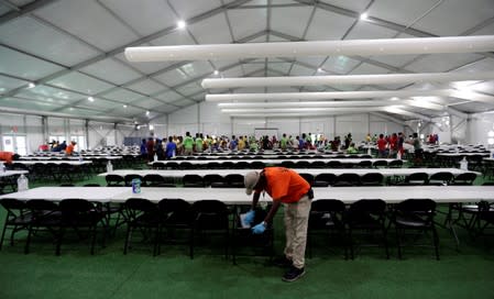 In this July 9, 2019, photo, a staff member cleans in a dinning hall at the U.S. government's newest holding center for migrant children in Carrizo Springs