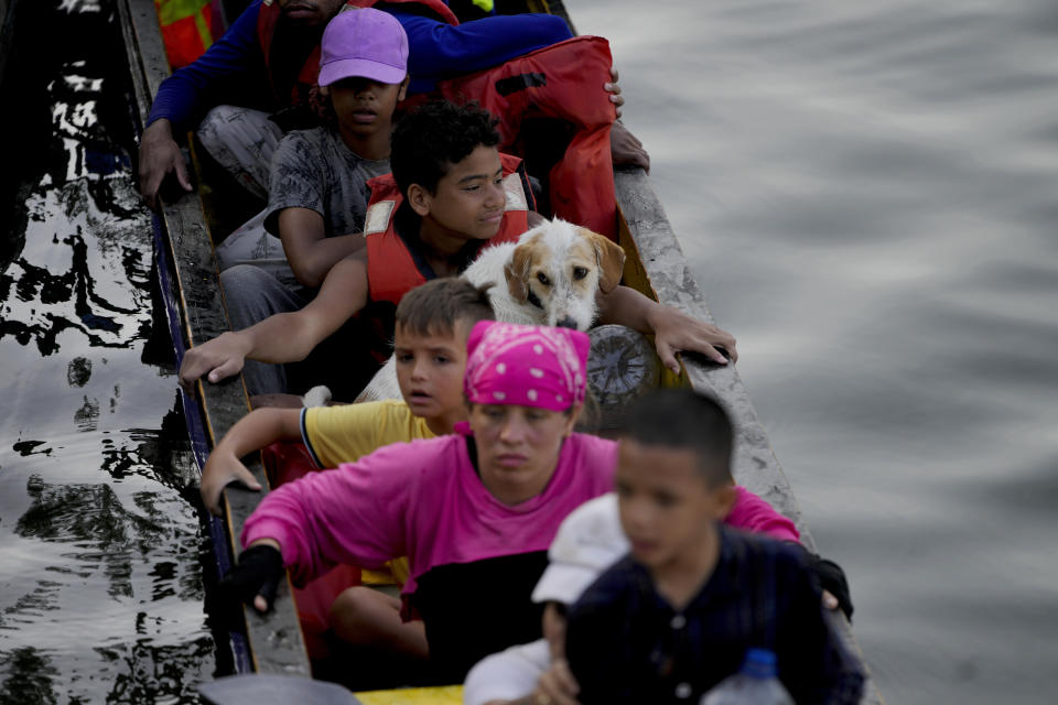 Joshua Morales travels with his dog Toby on his lap on a boat of migrants, after they walked across the Darien Gap from Colombia, in Bajo Chiquito, Panama, Saturday, May 6, 2023. Morales is the son of María Chirino Sánchez, 34, who left Venezuela one month earlier in a group of 10 relatives, including her husband, four children and dog Toby. (AP Photo/Natacha Pisarenko)