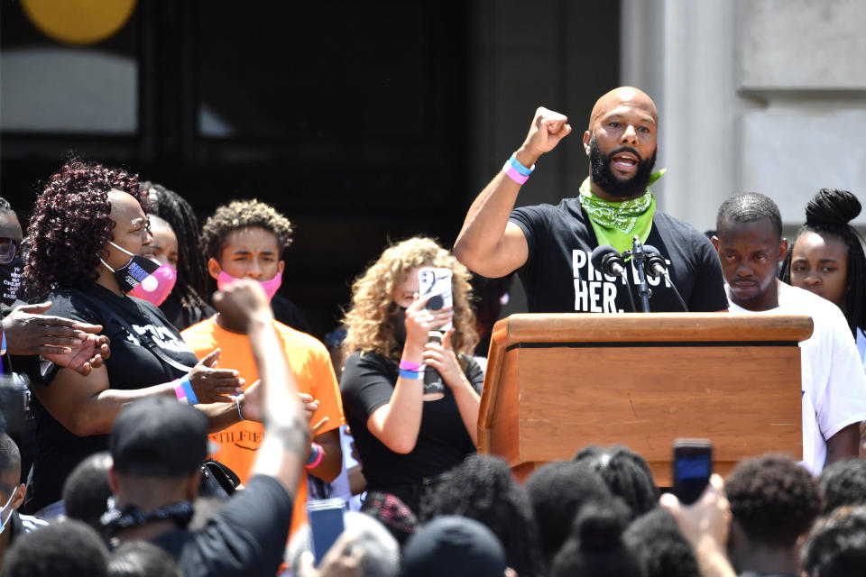 As Tamika Palmer, left, the mother of Breonna Taylor looks on, the artist Common addresses the crowd gathered on the steps of at the Kentucky State Capitol in Frankfort, Ky., Thursday, June 25, 2020. The rally was held to demand justice in the death of Taylor who was killed in her apartment by members of the Louisville Metro Police Department on March 13, 2020. (AP Photo/Timothy D. Easley)