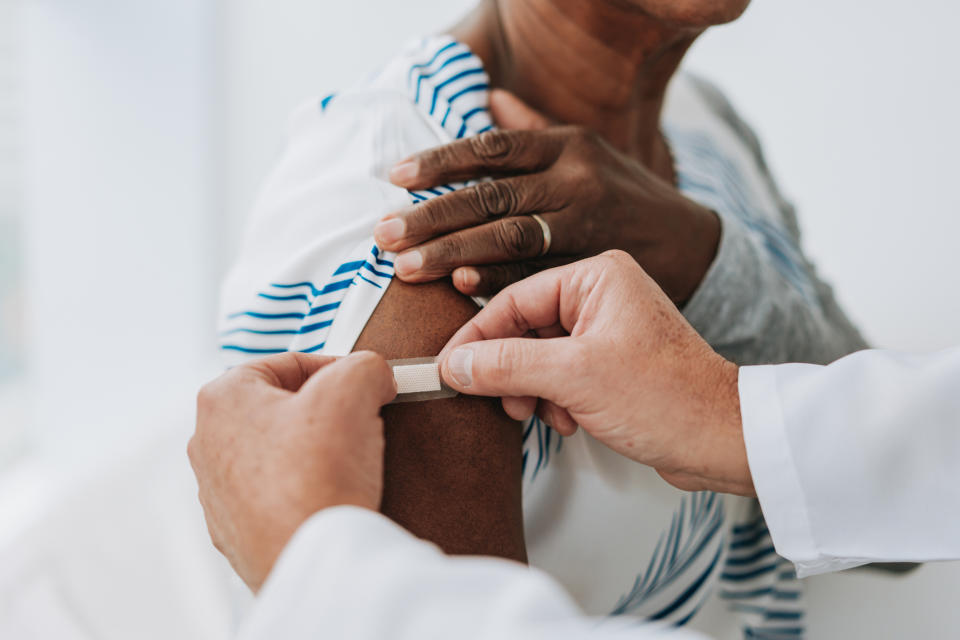 A person receives a band-aid on their arm from a healthcare professional after an injection