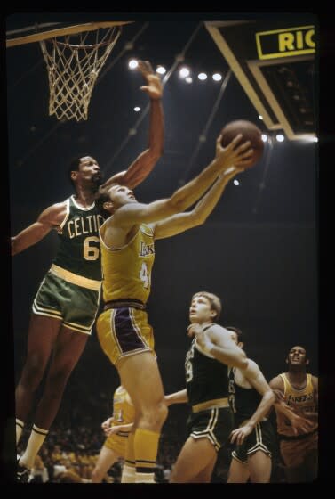 Jerry West #44 of the Los Angeles Lakers attempts a reverse layup against Bill Russell #6 of the Boston Celtics