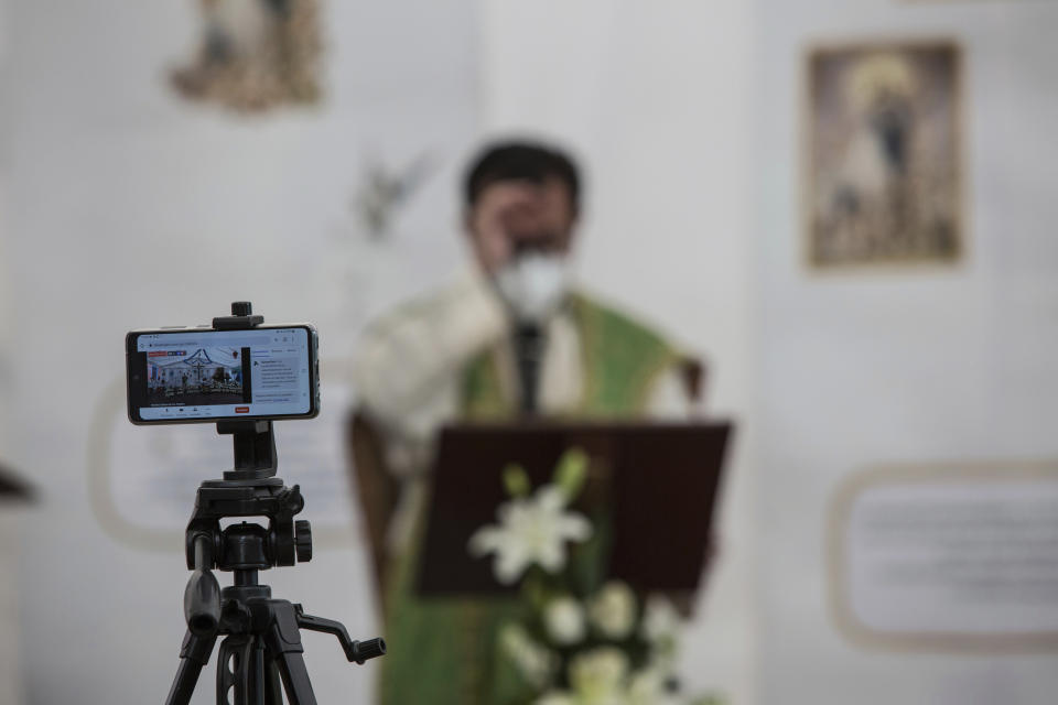 Rev. Adrian Vazquez's cell phone is set on a tripod live streaming an outdoor Mass held under a tent just outside the quake-damaged Our Lady of the Angels Catholic church which is undergoing restorations, in the Guerrero neighborhood of Mexico City, Sunday, Aug. 7, 2022. While there’s still no fixed end date for the restoration of the temple that was damaged in the Sept. 19, 2017 earthquake, Vazquez said the church is showing signs of rebirth. (AP Photo/Ginnette Riquelme)