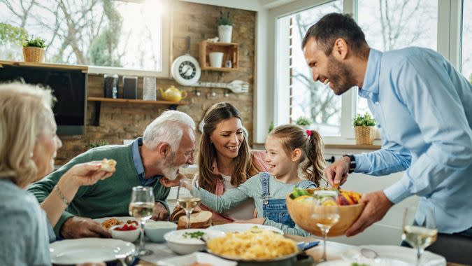 Happy multi-generation family gathering around dining table and having fun during a lunch.