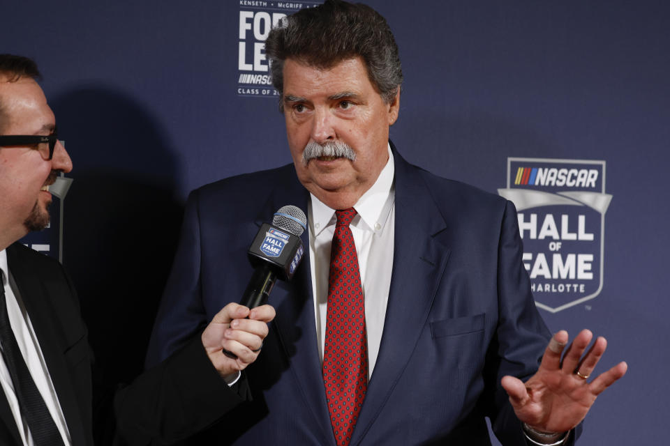 Mike Helton, right, talks as he arrives at the NASCAR Hall of Fame for the Hall of Fame inductions in Charlotte, N.C., Friday, Jan. 20, 2023. Helton is the recipient of the Landmark Award for Outstanding Contributions to NASCAR. (AP Photo/Nell Redmond)