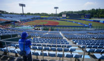 A steward watches from the empty grandstands during the softball game between Japan and Australia at the 2020 Summer Olympics, Wednesday, July 21, 2021, in Fukushima, Japan. (AP Photo/Jae C. Hong)