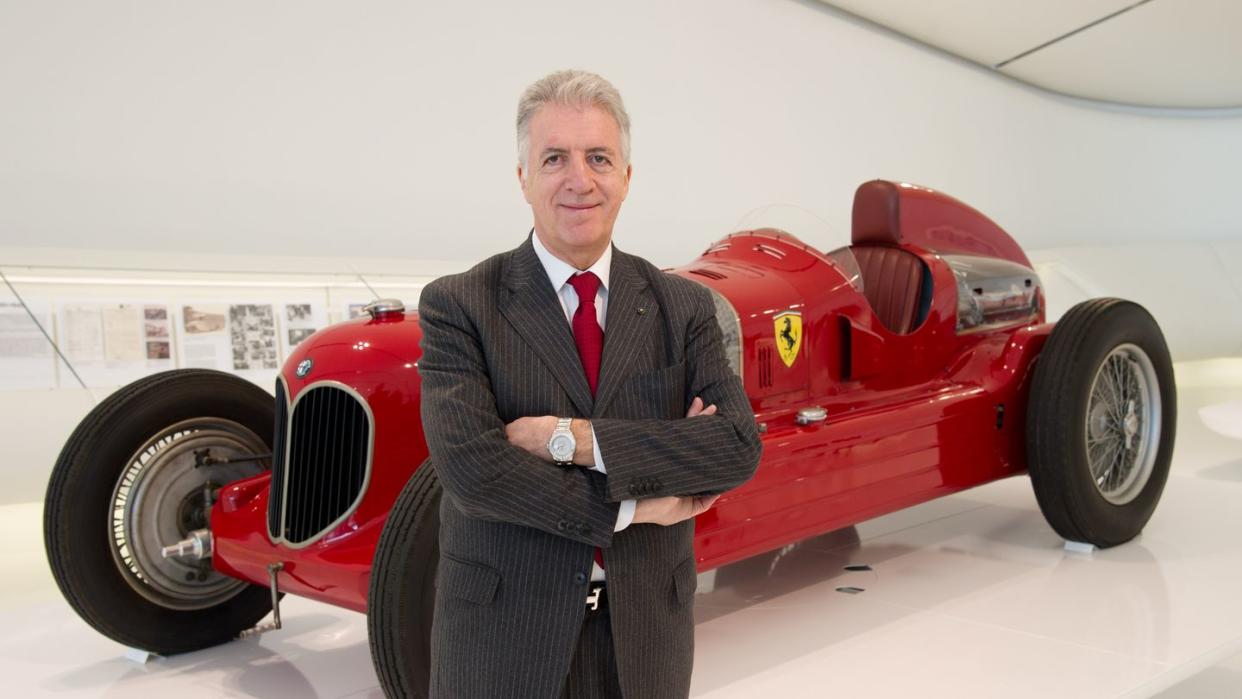 piero ferrari standing in front of a vintage ferrari race car at a museum