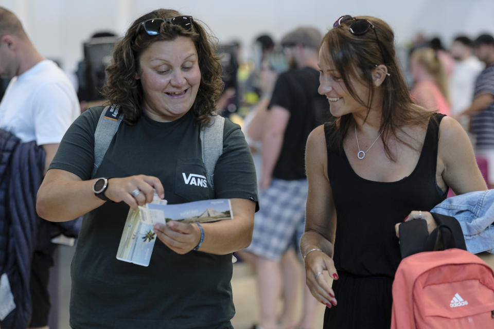 Tourists smile after checking in an alternate flight, at the Cancun airport in Mexico, Monday, Sept. 23, 2019. British tour company Thomas Cook collapsed early Monday after failing to secure emergency funding, leaving tens of thousands of vacationers stranded abroad. (AP Photo/Victor Ruiz)