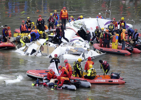 Emergency personnel retrieve the body of a passenger from the wreckage of a TransAsia Airways turboprop ATR 72-600 aircraft after it crashed in a river, in New Taipei City, February 4, 2015. REUTERS/Stringer