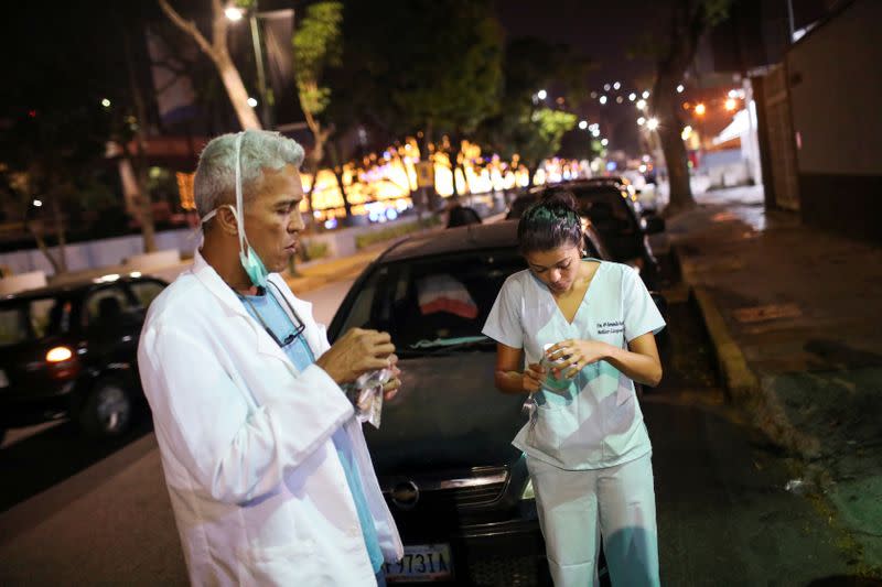 Los doctores Carlos Martínez y María Martínez comen un refrigerio mientras esperan en la fila para obtener combustible en una gasolinera, durante una cuarentena a debido al brote de la enfermedad por coronavirus (COVID-19), en Caracas.