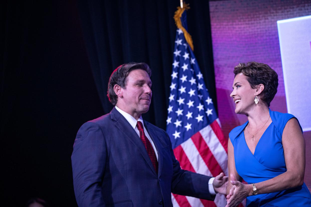 Florida Gov. Ron DeSantis interacts with Kari Lake on stage at the Unite and Win Rally organized by Turning Point Action in Phoenix on Aug. 14, 2022.