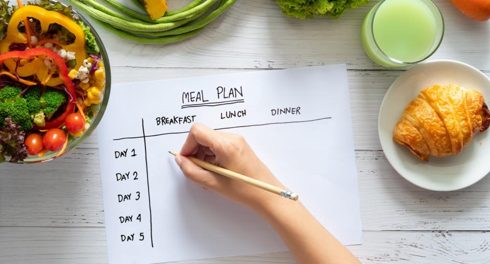 Woman writes meal plan for the week. (Getty Images)