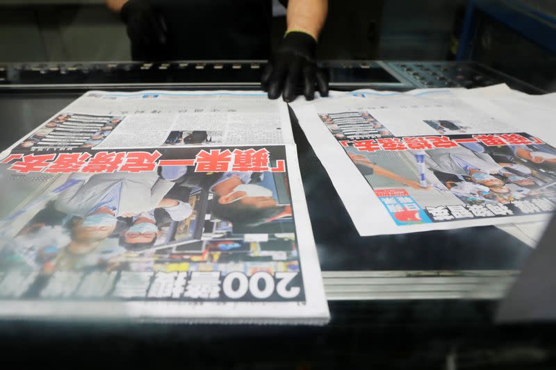 An employee checks the print quality of copies of the Apple Daily newspaper, published by Next Media Ltd, with a headline "Apple Daily will fight on" at the company's printing facility, in Hong Kong