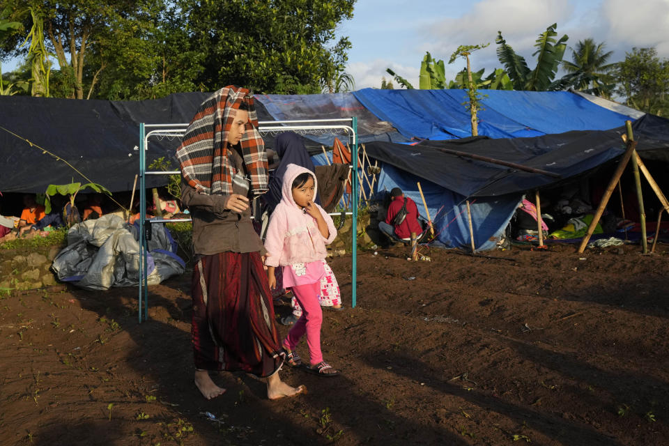 People displaced by Monday's earthquake walk near temporary shelters in Cianjur, West Java, Indonesia, Thursday, Nov. 24, 2022. The 5.6 magnitude earthquake left hundreds dead, injures and missing as buildings crumbled and terrified residents ran for their lives on Indonesia's main island of Java. (AP Photo/Tatan Syuflana)