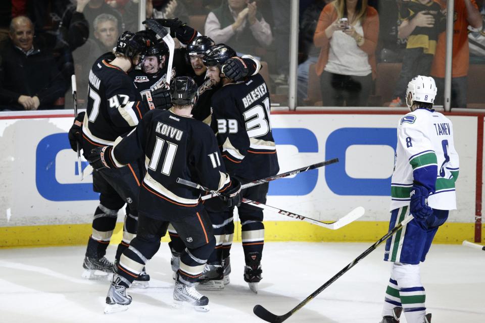 The Anaheim Ducks players celebrate a goal by Teemu Selanne (8), of Finland, next to Vancouver Canucks' Chris Tanev, right, during the first period of an NHL hockey game on Wednesday, Jan. 15, 2014, in Anaheim, Calif. (AP Photo/Jae C. Hong)