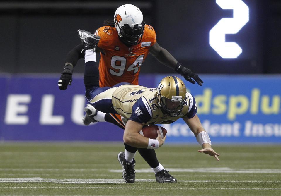 Winnipeg Blue Bombers QB Brian Brohm (12) is tripped by Khreem Smith (94) of the B.C Lions during the second half of their CFL football game in Vancouver, British Columbia, September 13, 2014. REUTERS/Ben Nelms (CANADA - Tags: SPORT FOOTBALL)