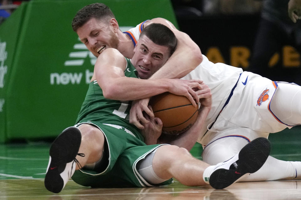 Boston Celtics guard Payton Pritchard, front, wrestles New York Knicks center Isaiah Hartenstein for the ball during the second half of an NBA basketball game, Friday, Dec. 8, 2023, in Boston. (AP Photo/Charles Krupa)